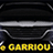 Face avant élégante d'une voiture noire avec calandre chromée et phares allumés. Logo jaune GARRION visible sous le pare-chocs.
